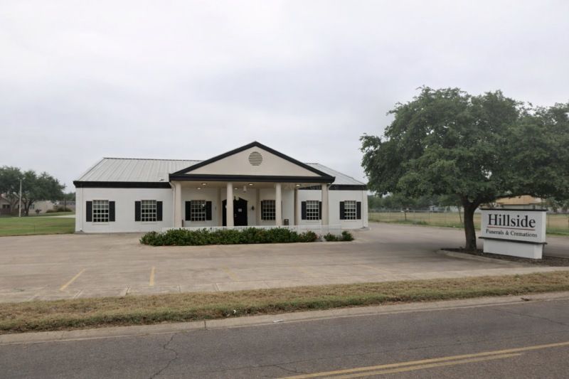 White traditional funeral facility with black shutters and signage for Funeral Homes Rio Bravo, TX on a quiet roadside