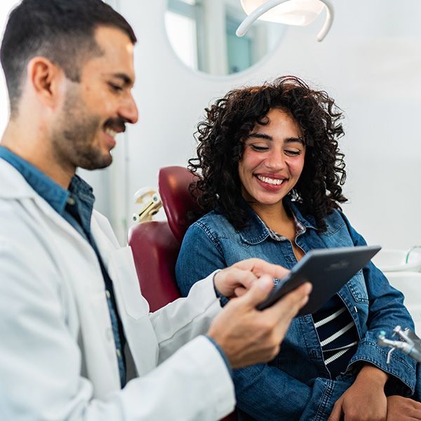Dentist showing a tablet to a smiling patient in a dental chair
