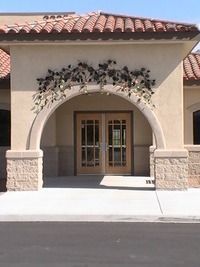 Building entrance with arched doorway, double glass doors, and terracotta roof tiles