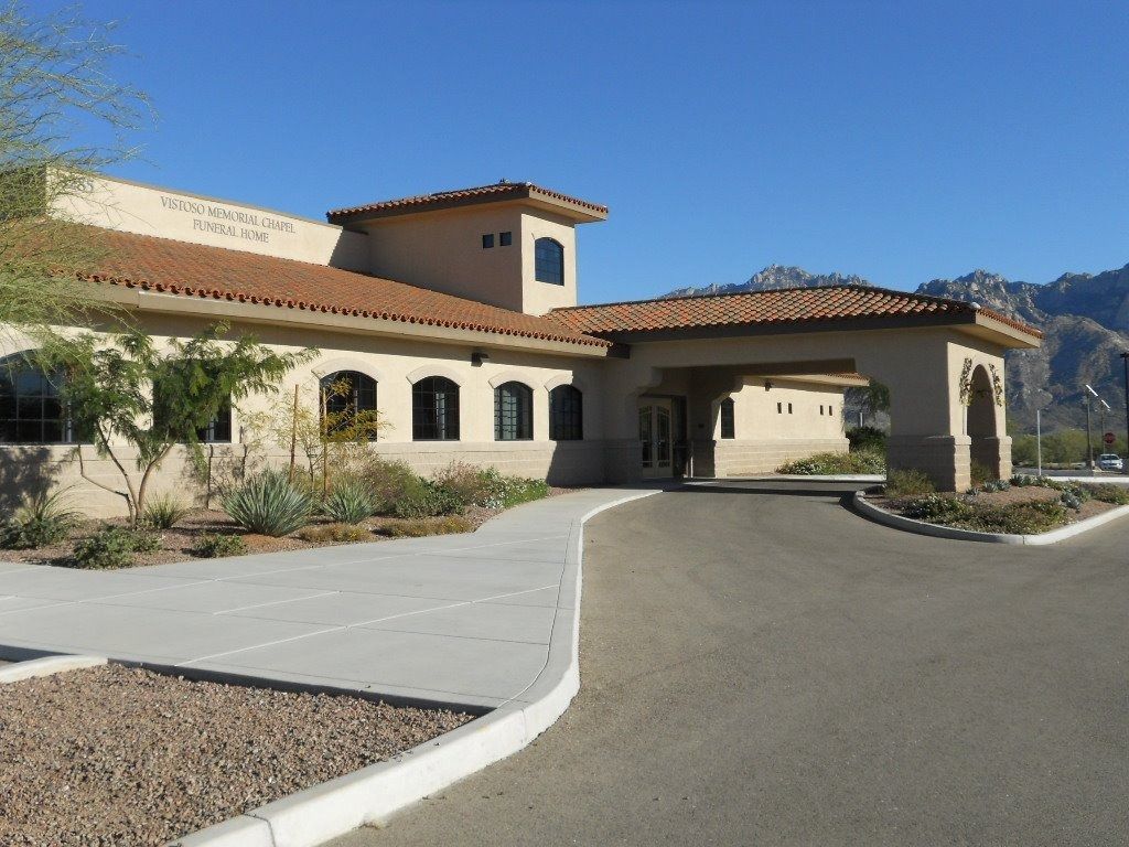 House with arched windows, tan stucco, red tile roof, and a curved driveway