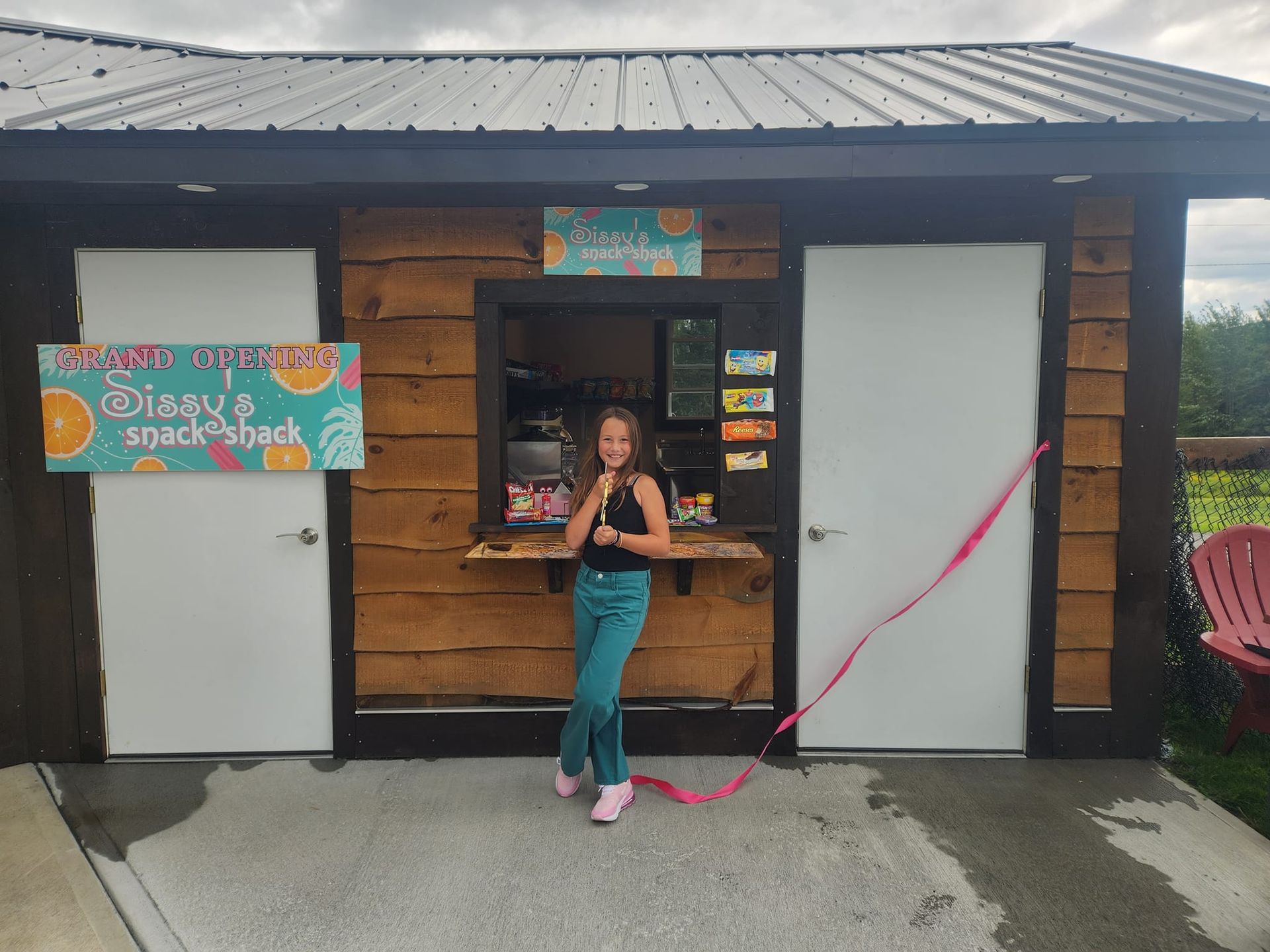 A little girl is standing in front of a Sissy's snack shack.