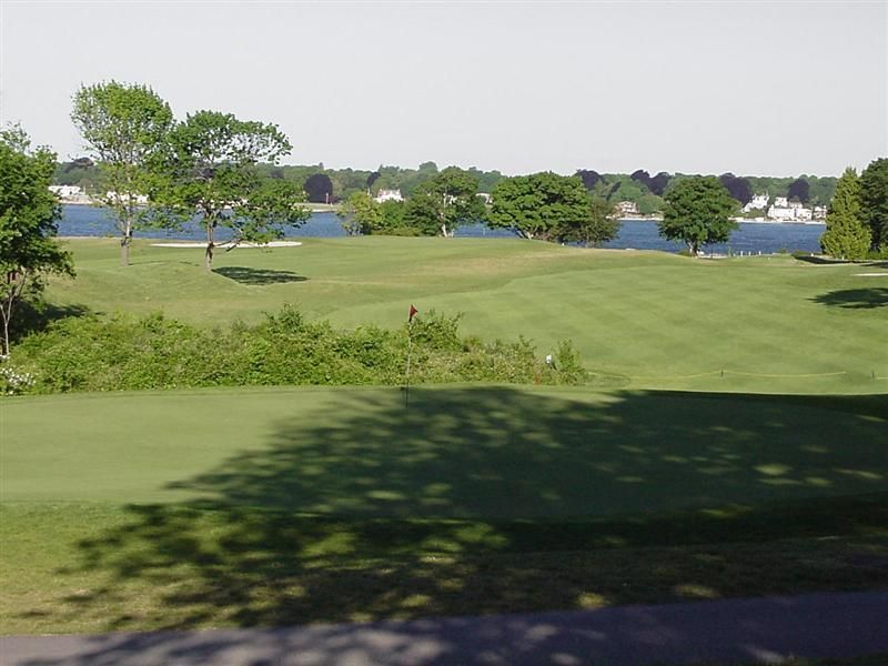 Golf course with green fairway, trees, and a pond in the background
