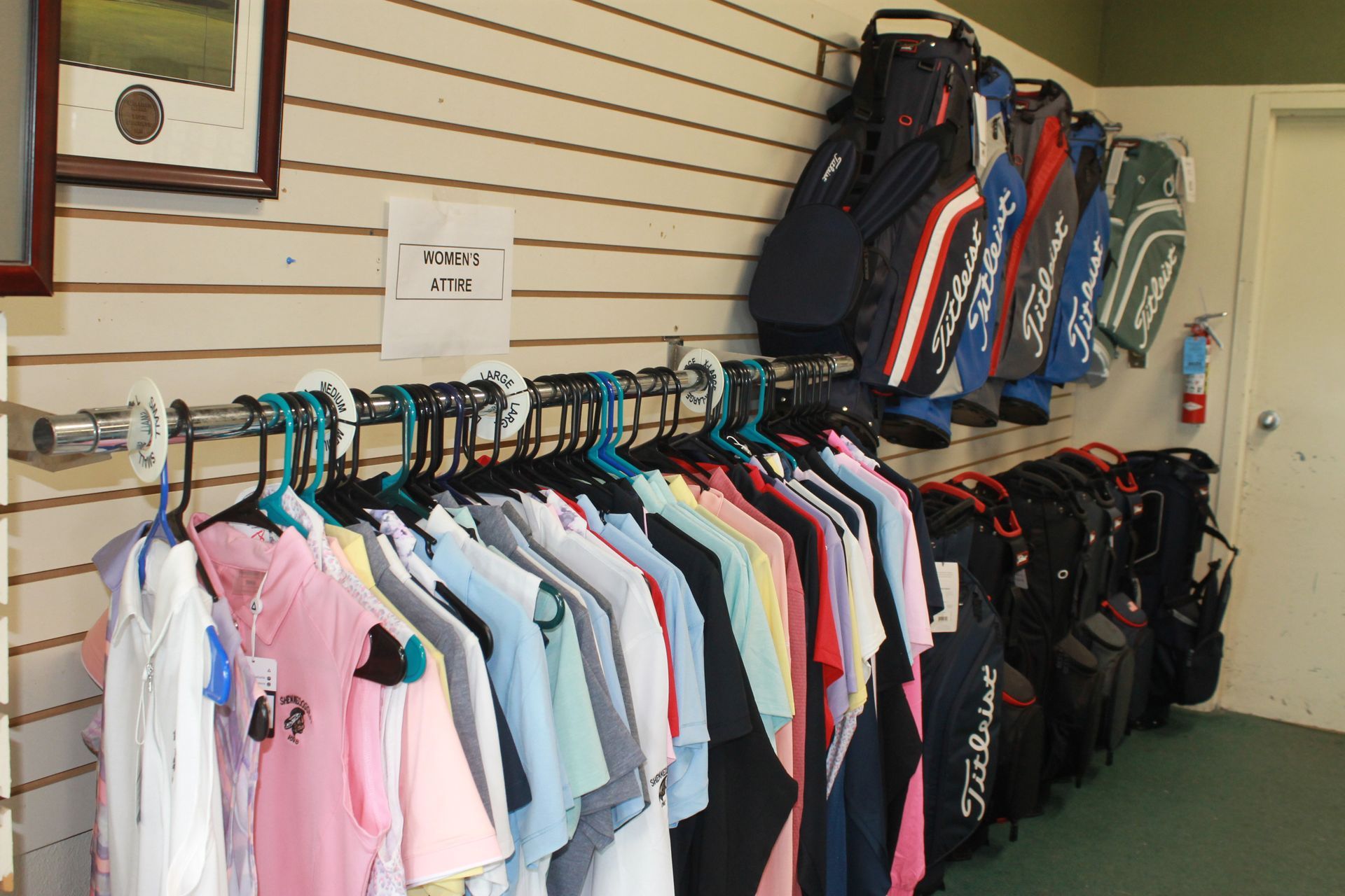 Clothing rack with colorful shirts and tennis bags displayed in a sports shop
