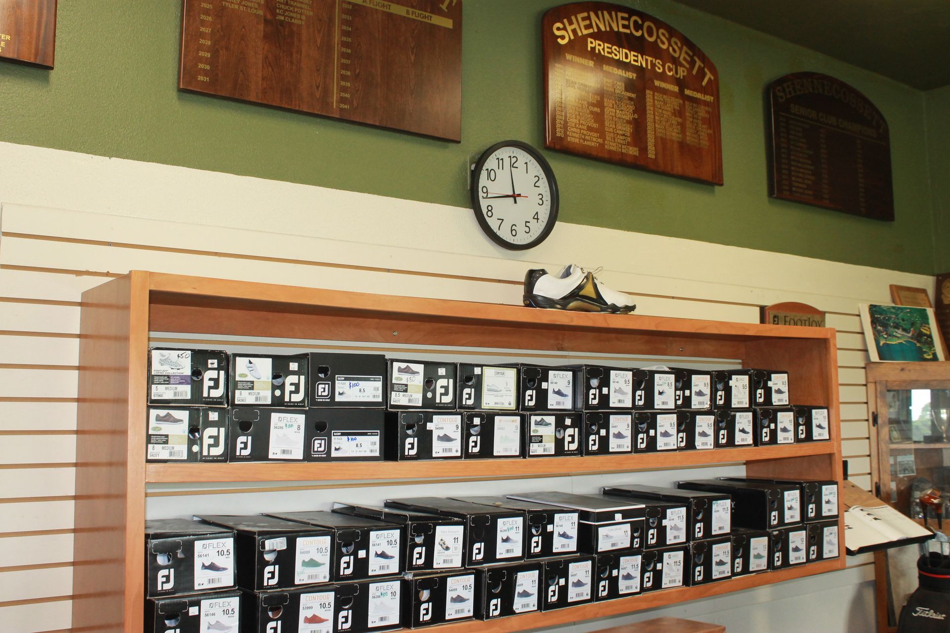 Retail display of small black-and-white boxed items on shelves in a store, with a wall clock above