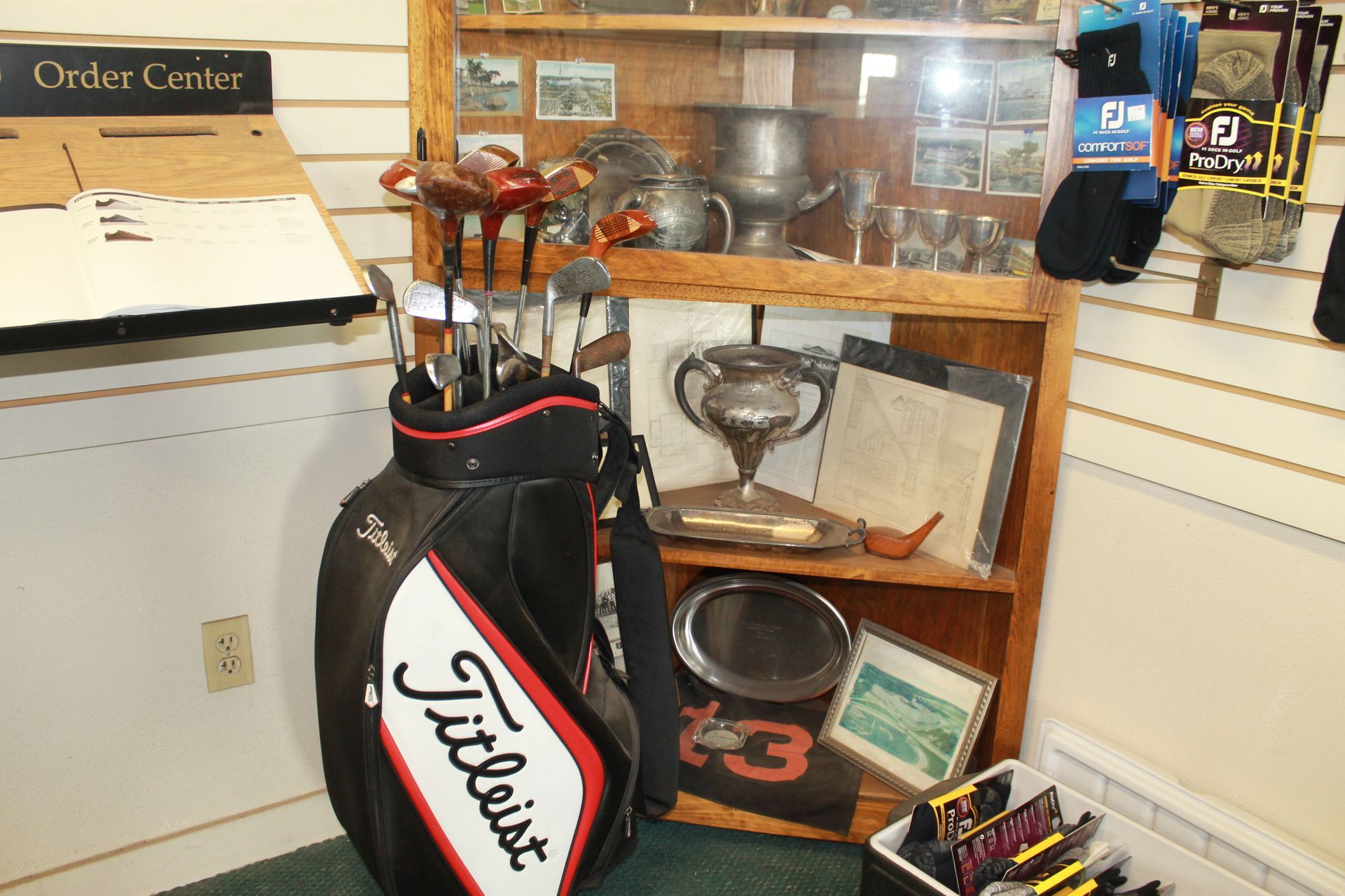 Golf bag in a shop display, beside an order center counter and shelves of assorted items.