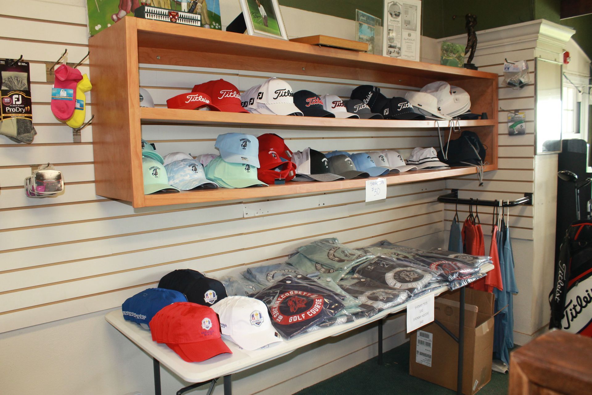 Caps and hats displayed on shelves and a table in a small shop display area
