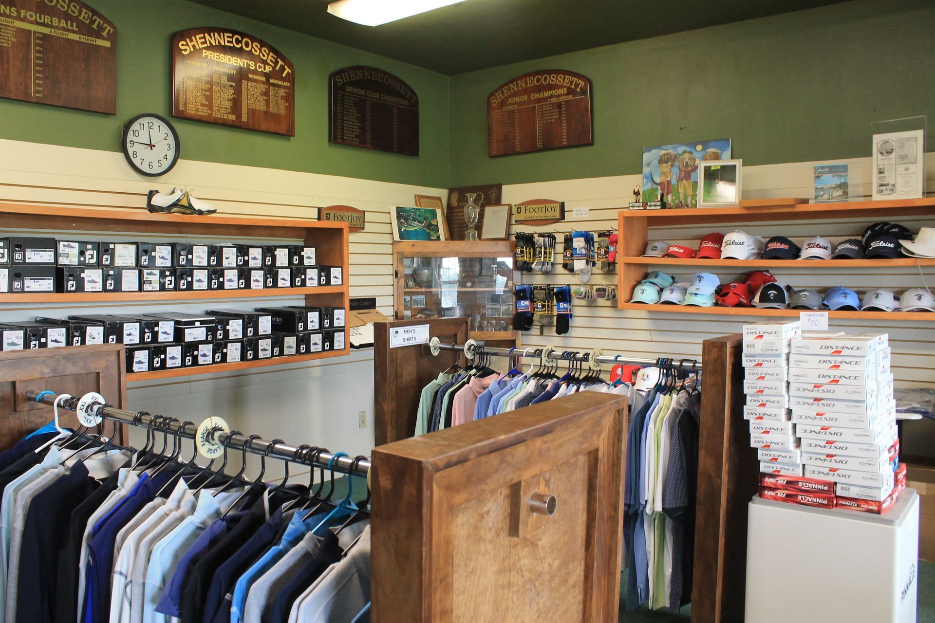Clothing store interior with racks of shirts, folded apparel shelves, and a wooden display cabinet