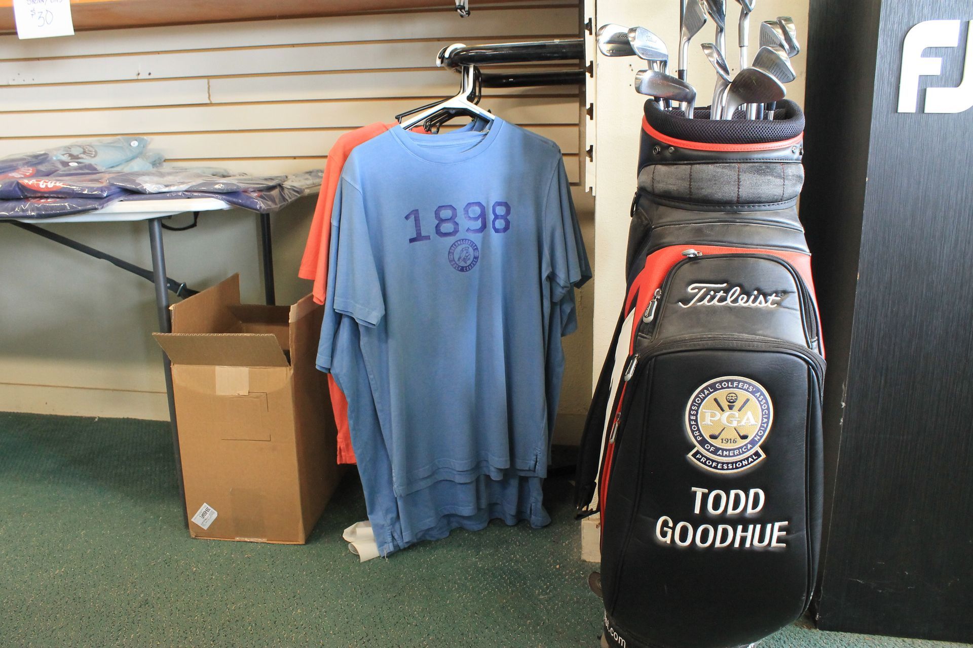 Golf shop display with hanging shirts, golf clubs, and a black golf bag labeled 