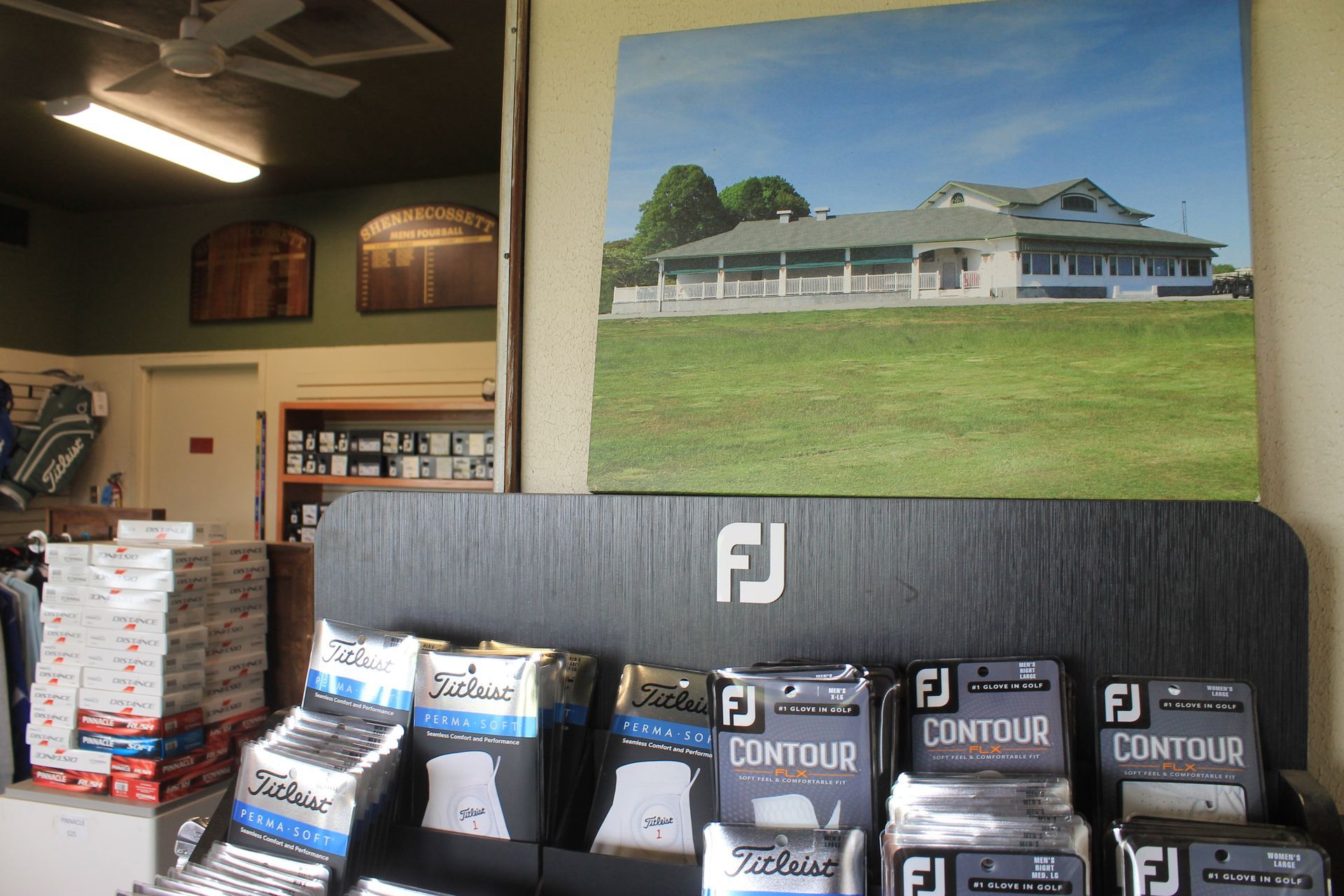 Shop interior with a large framed building photo above stacks of Contour FJ product boxes.