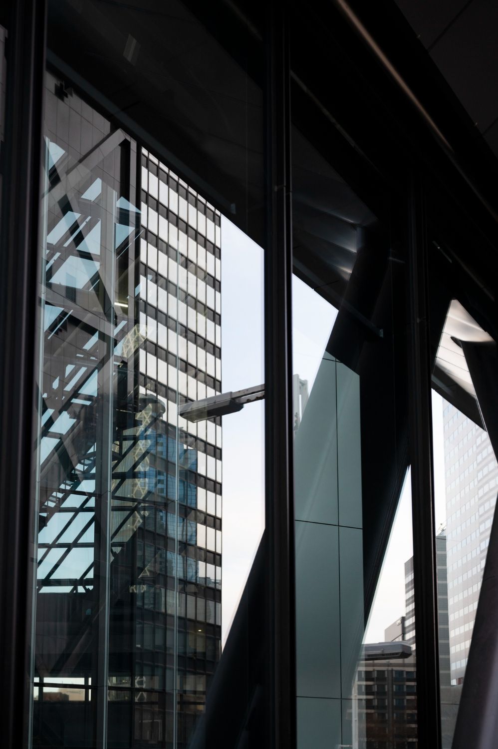 Modern glass office buildings viewed through dark structural beams in an urban setting