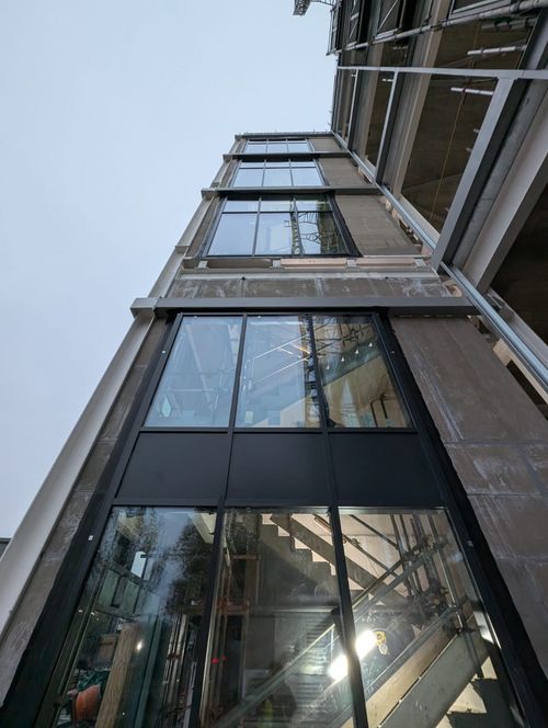 Looking up at a modern glass building with steel frames and reflections on the facade