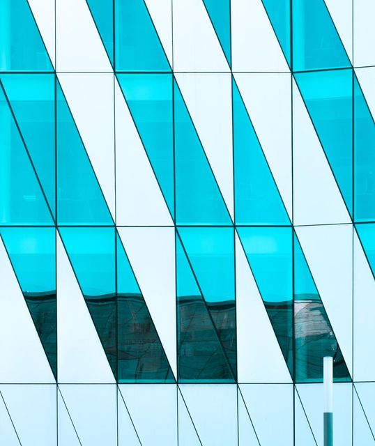 Blue-and-white geometric glass building facade with diagonal panels and reflections
