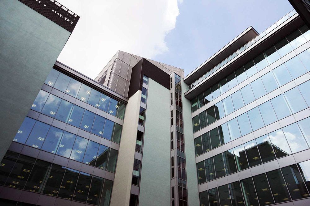 Modern glass office buildings viewed from below against a bright sky