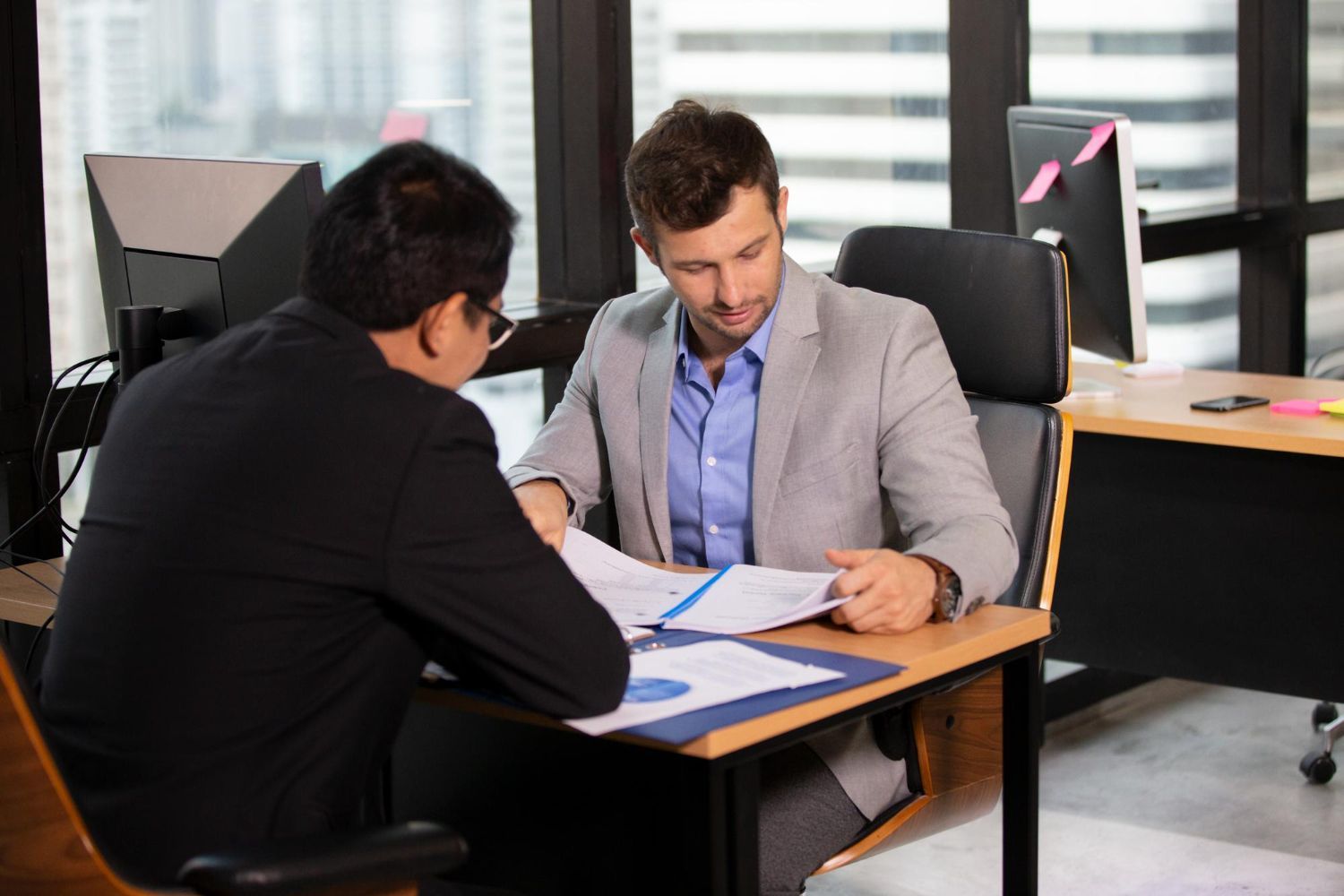 Two people reviewing documents across a desk in a modern office