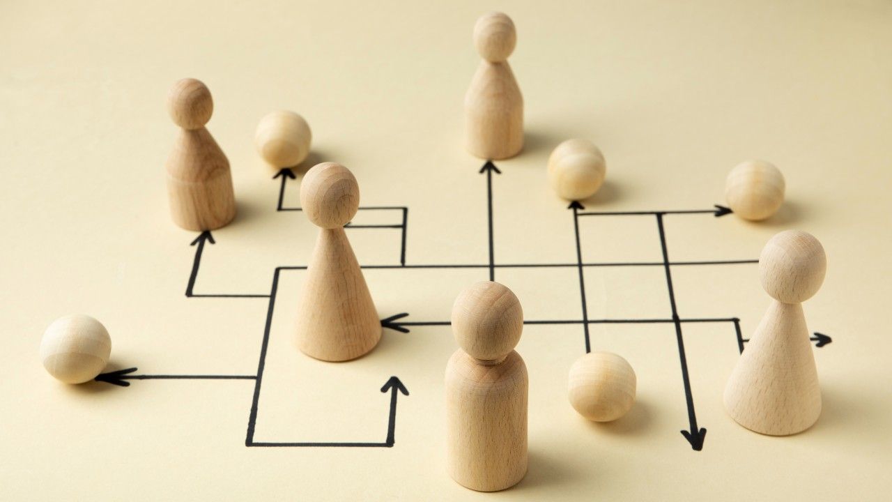 Un grupo de figuras de madera están sentadas sobre una mesa con flechas que apuntan en diferentes direcciones.