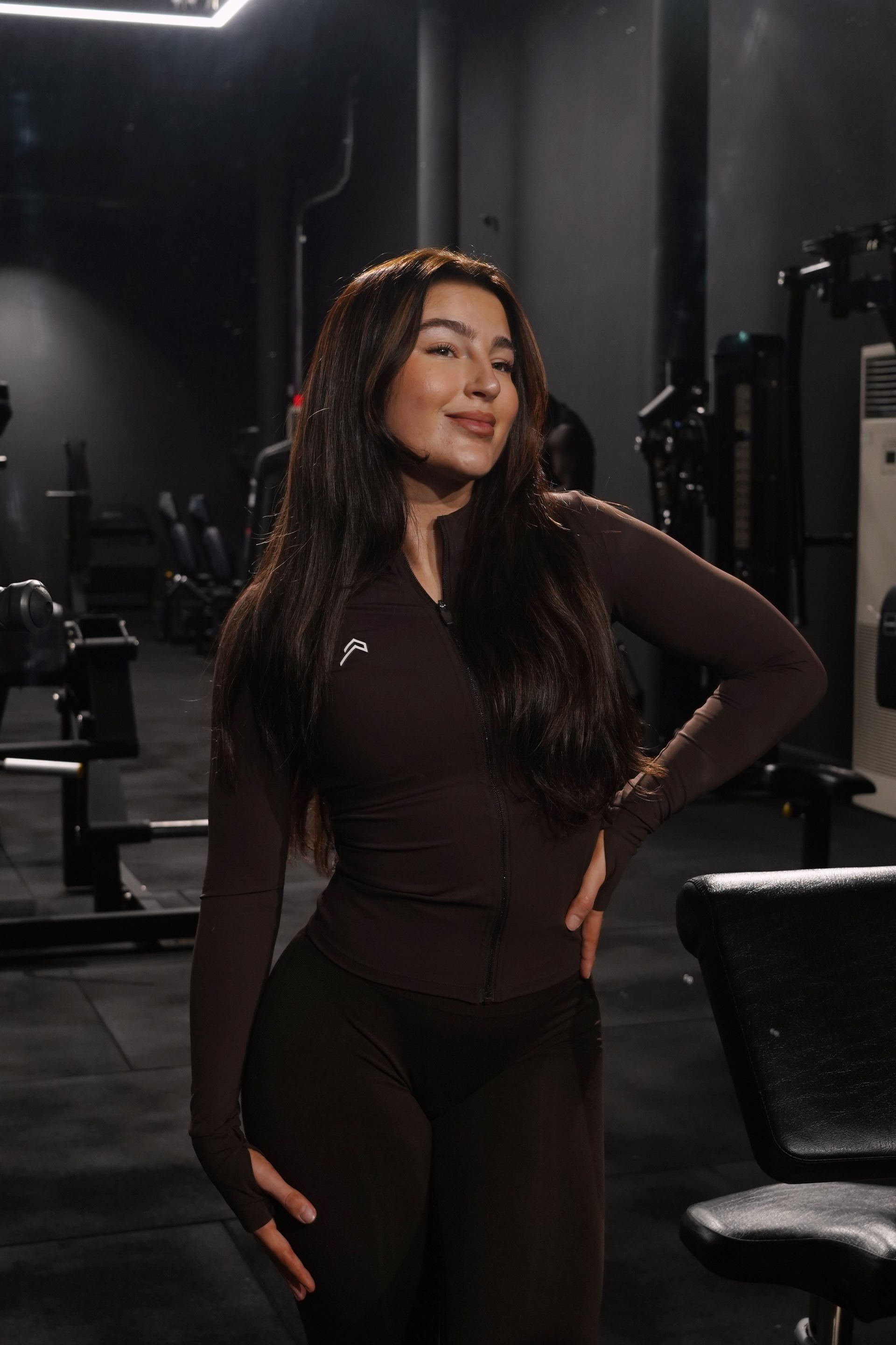 A woman in a black top and green shorts is standing in a dark room.