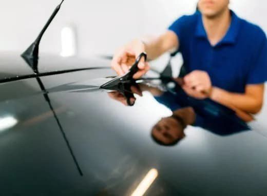 A man is cutting the windshield of a car with scissors.