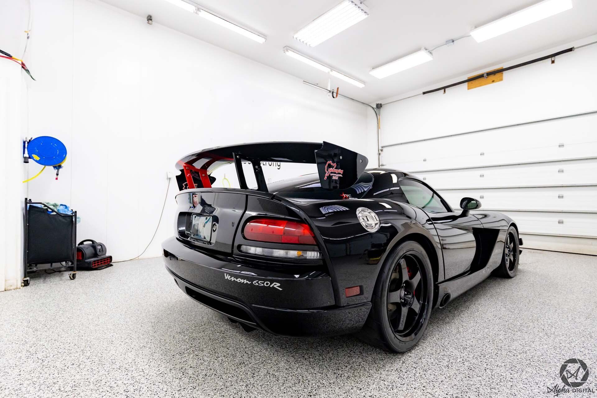 A black dodge viper is parked in a garage.