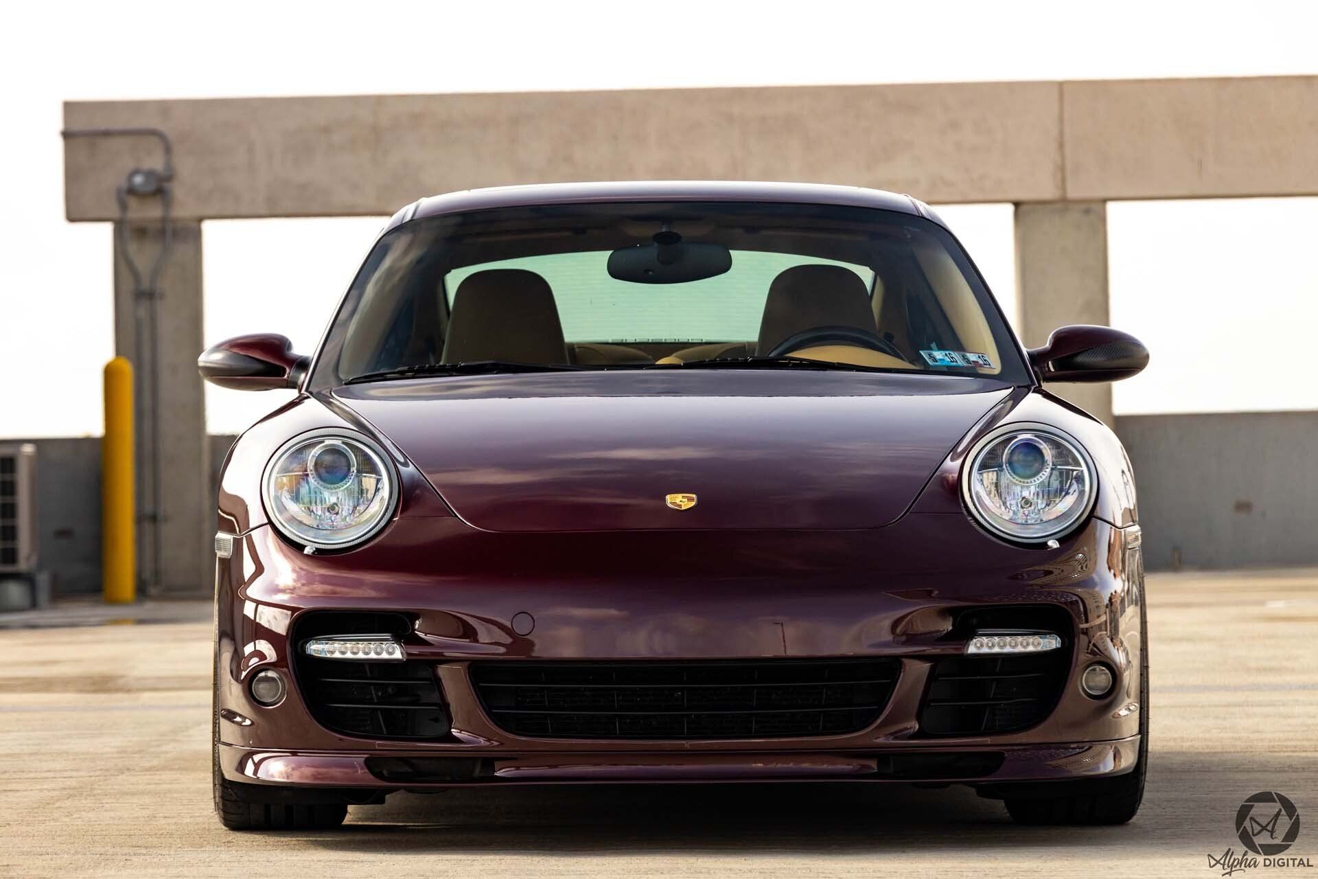 A burgundy porsche 911 turbo is parked in a parking garage.