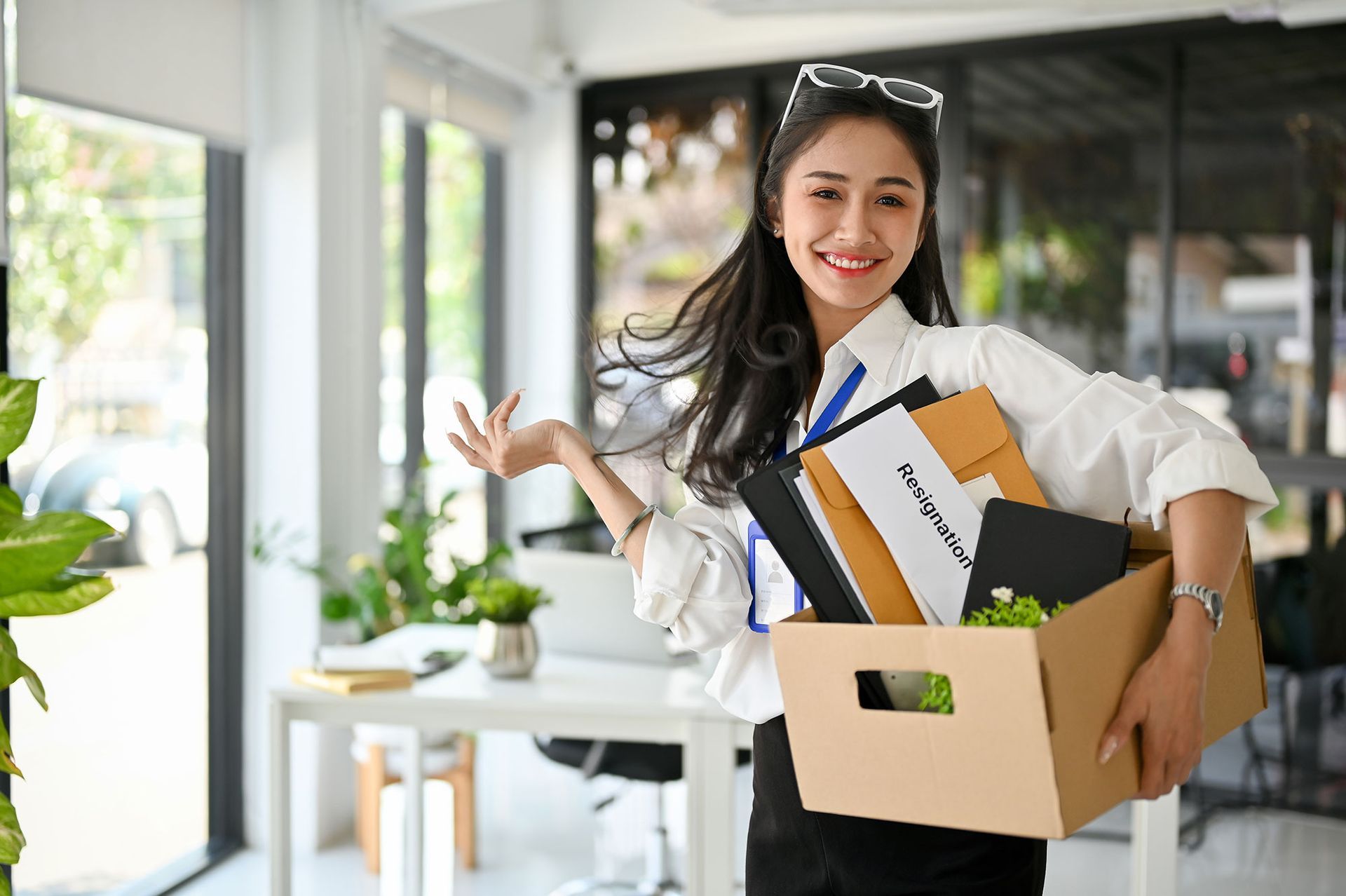 A woman is holding a box of her belongings in an office.