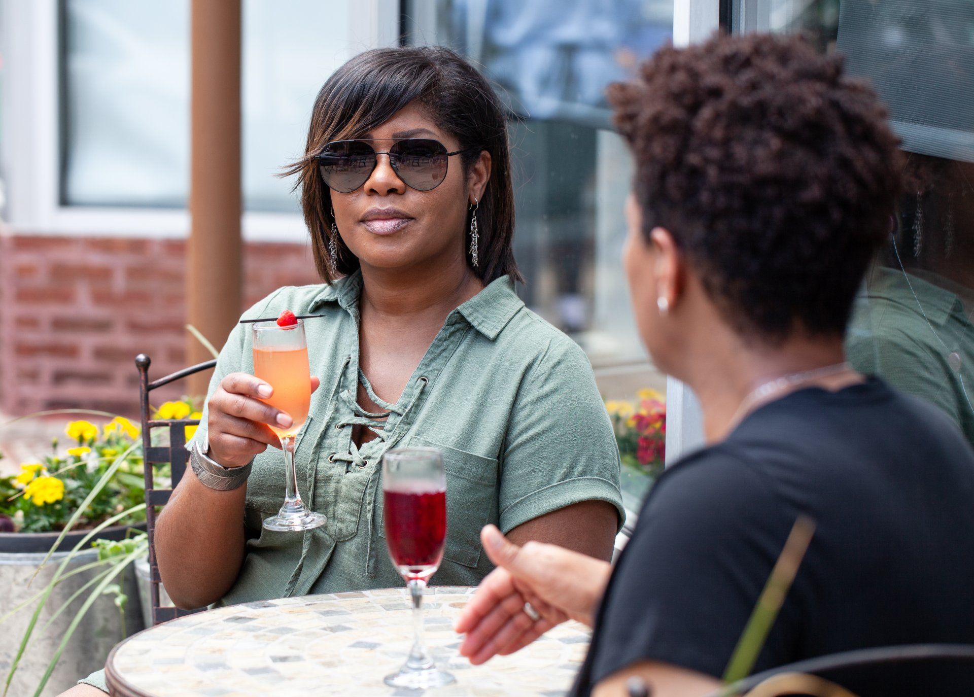 Two women are sitting at a table drinking wine and talking.