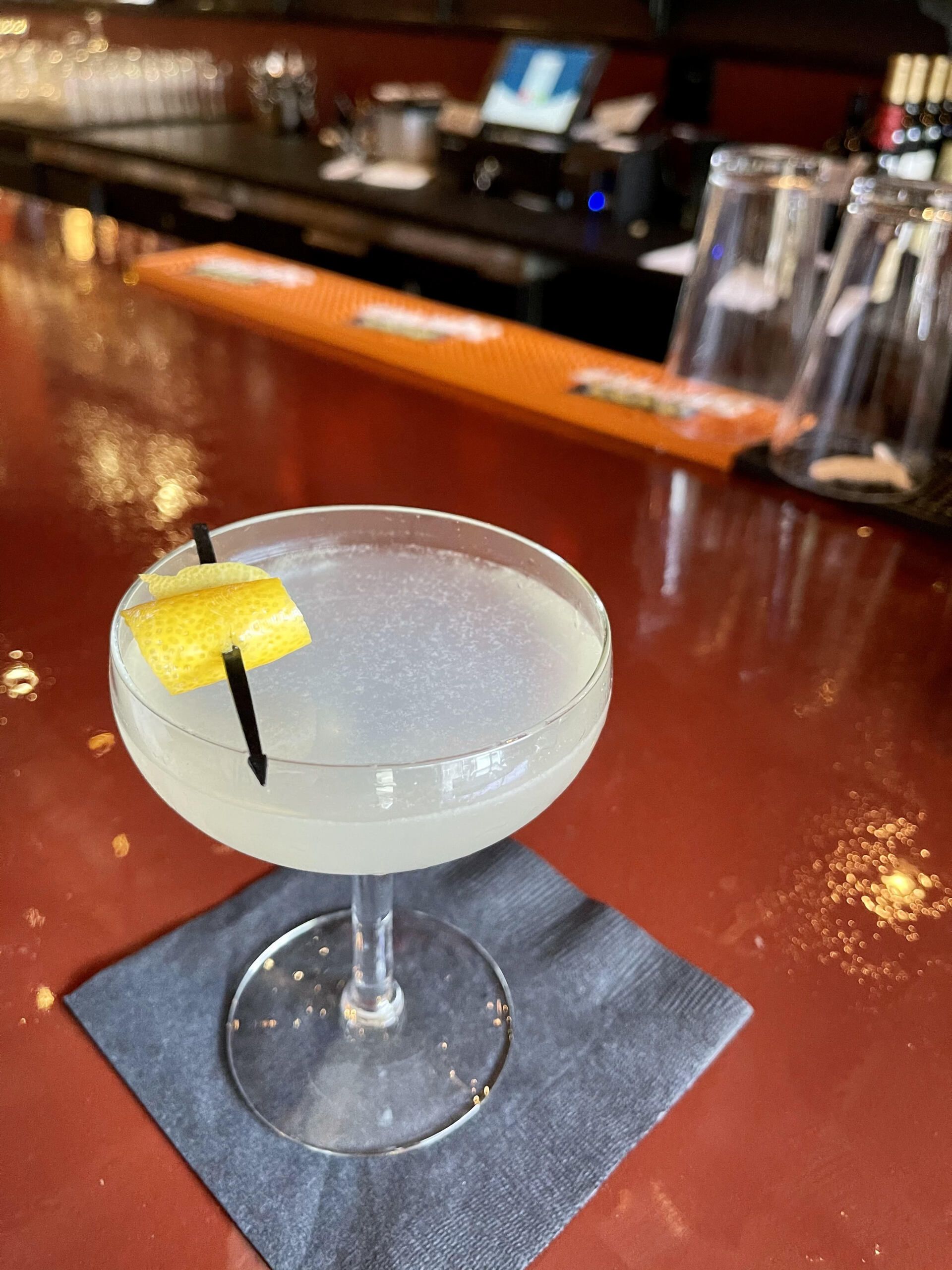 A close up of a cocktail on a napkin on a bar.