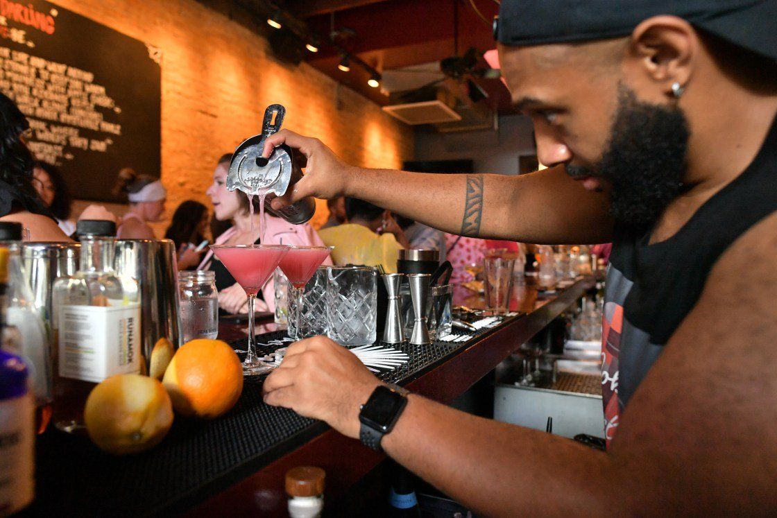 A man is pouring a drink into a martini glass.