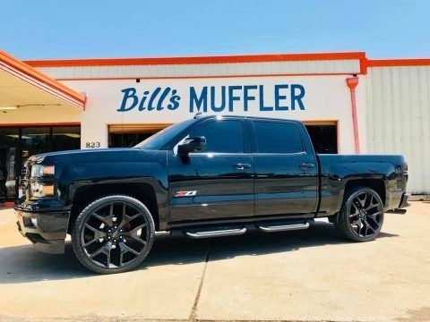 Black pickup truck parked outside Bill’s Muffler shop.