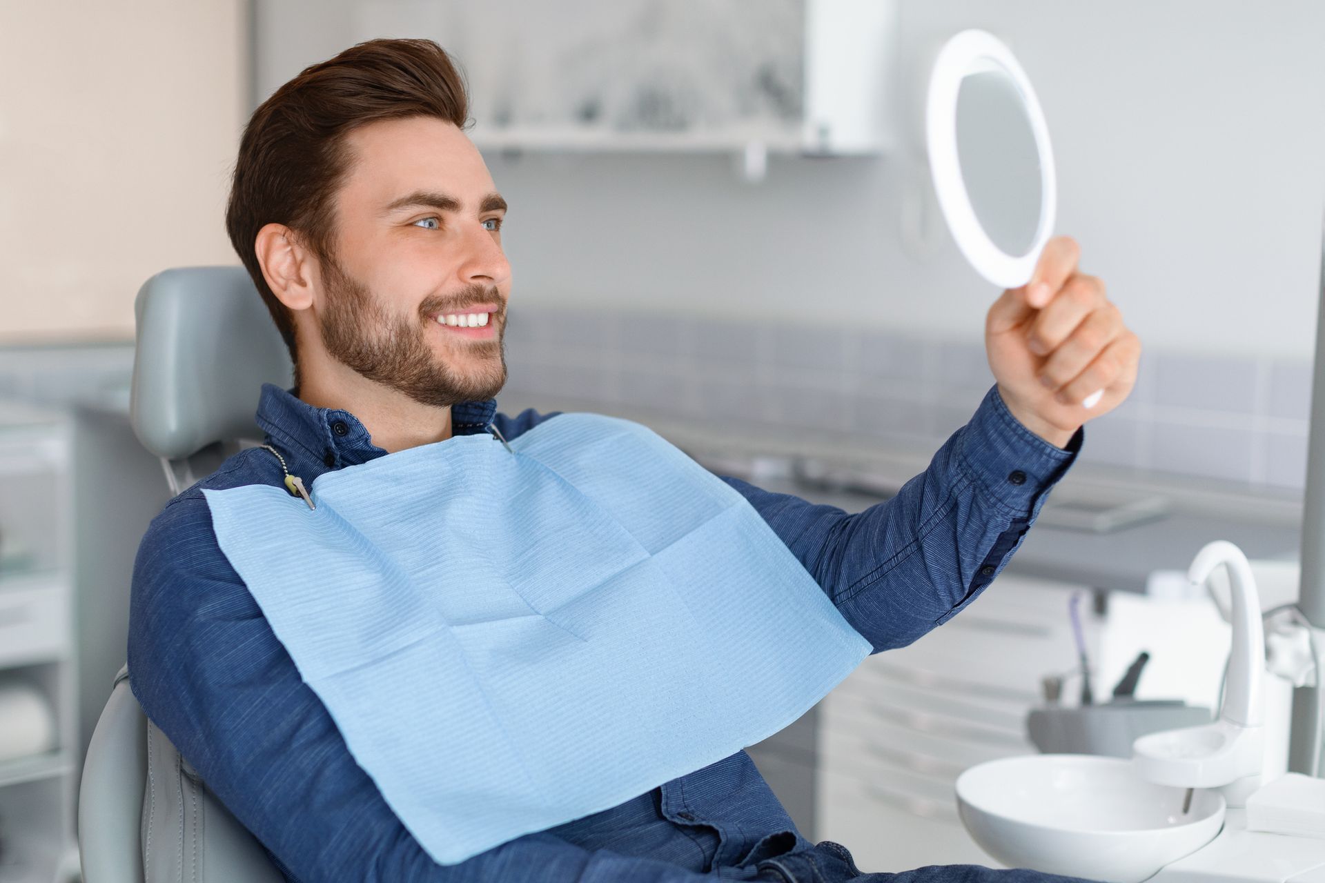 Smiling male patient in a dental chair holding a mirror at Blome Family Dentistry, trusted family de
