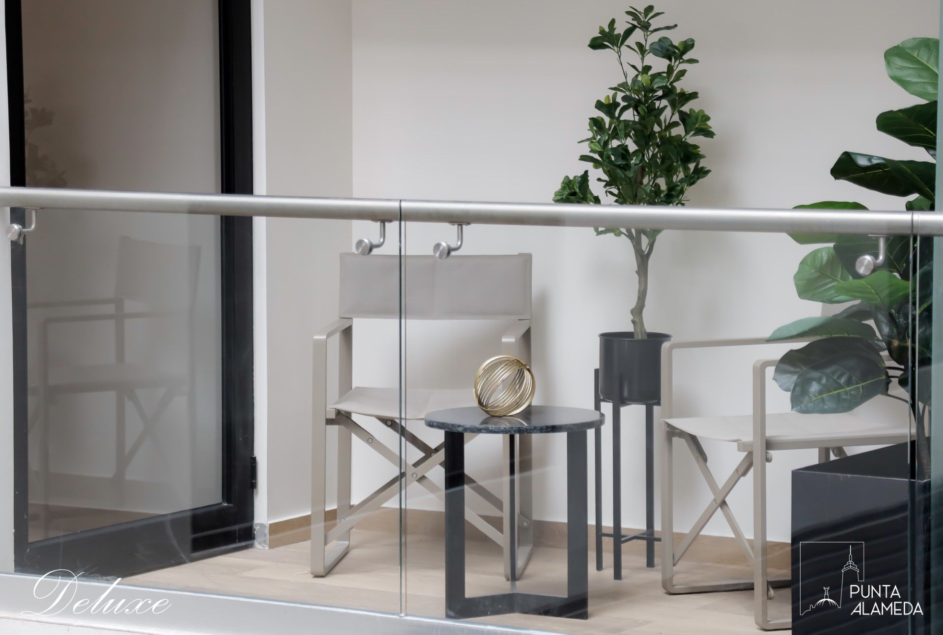 Un balcón con sillas, una mesa y una planta.