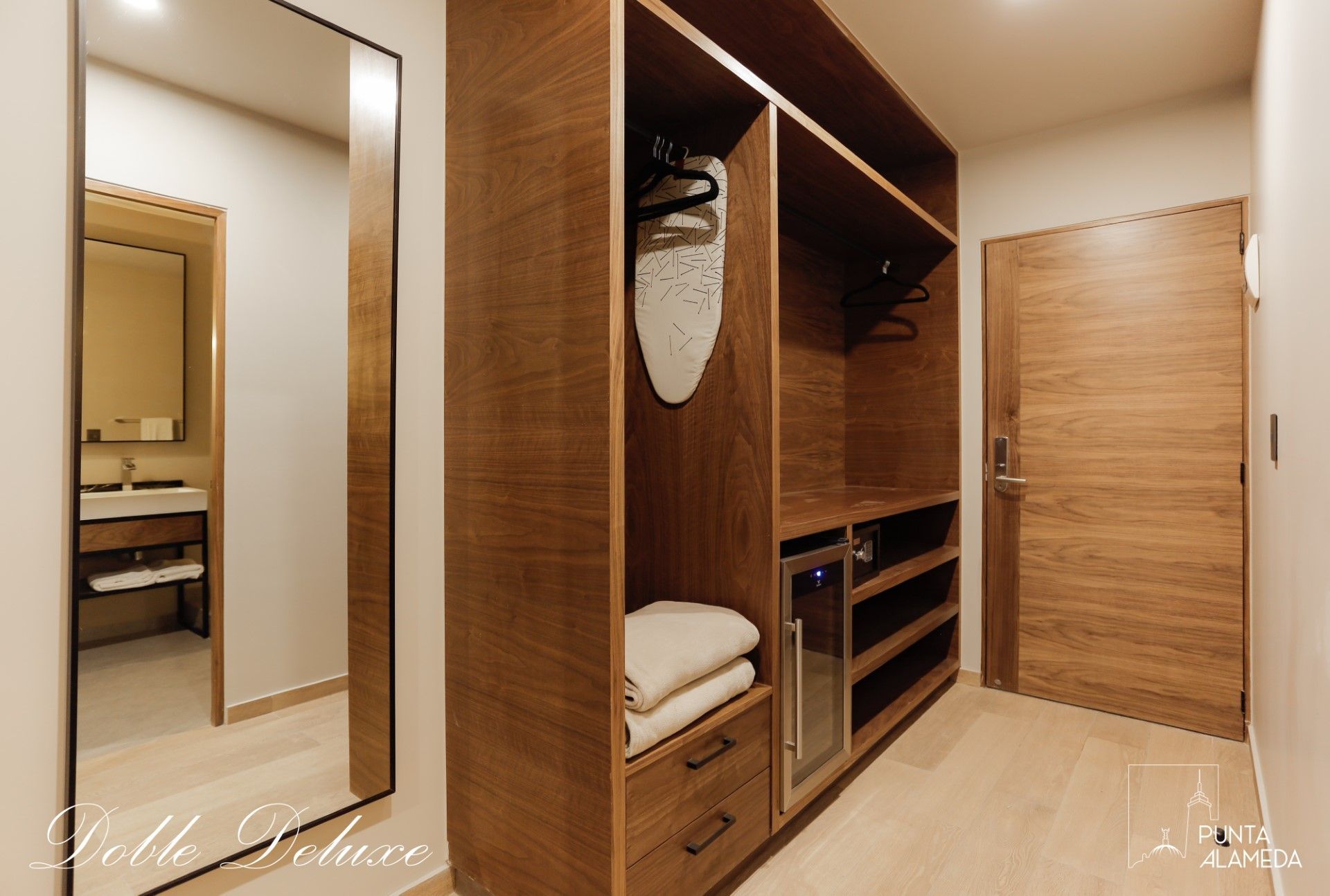 Una habitación de hotel con vestidor y un espejo grande.
