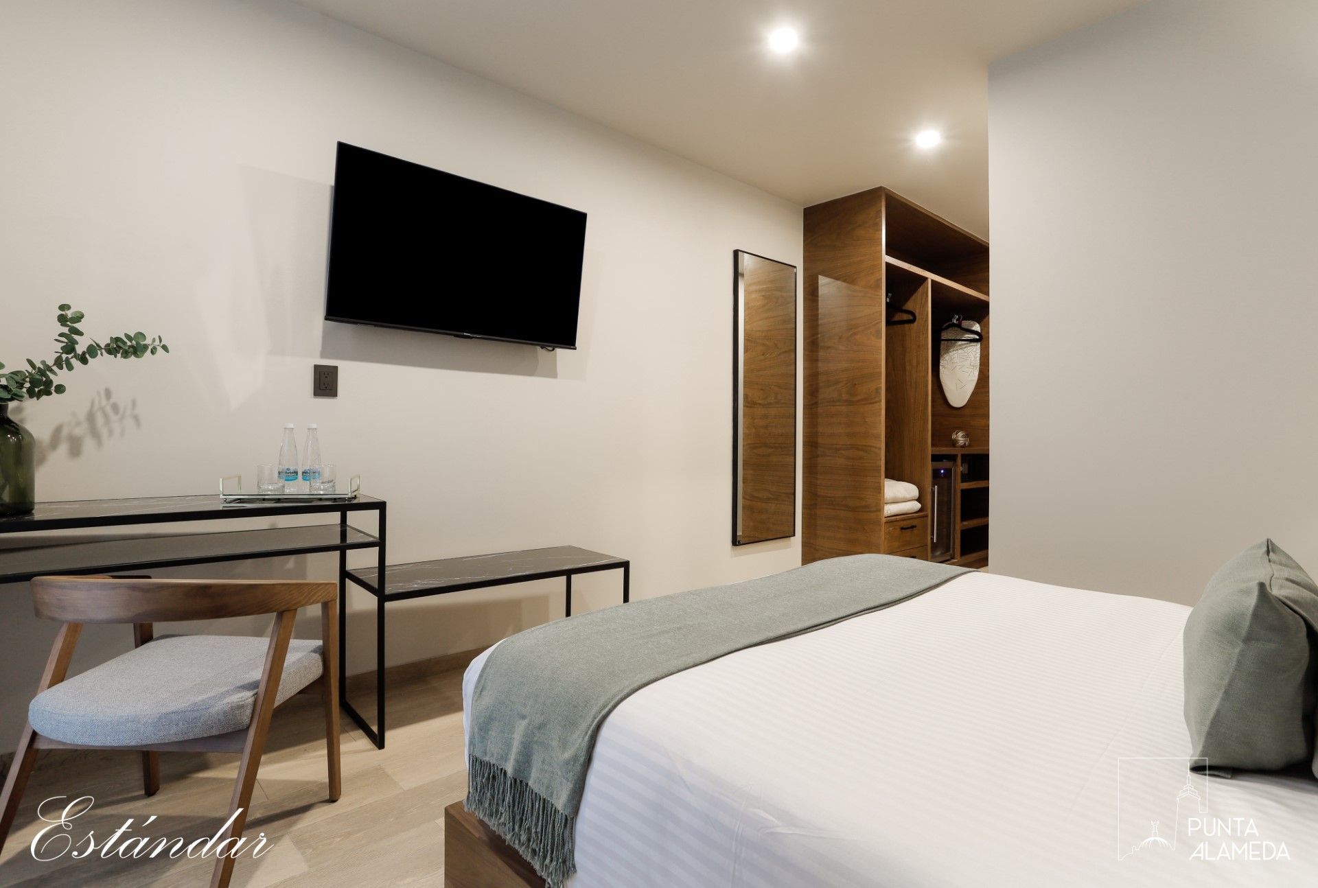 Una habitación de hotel con cama, escritorio, silla y televisión.