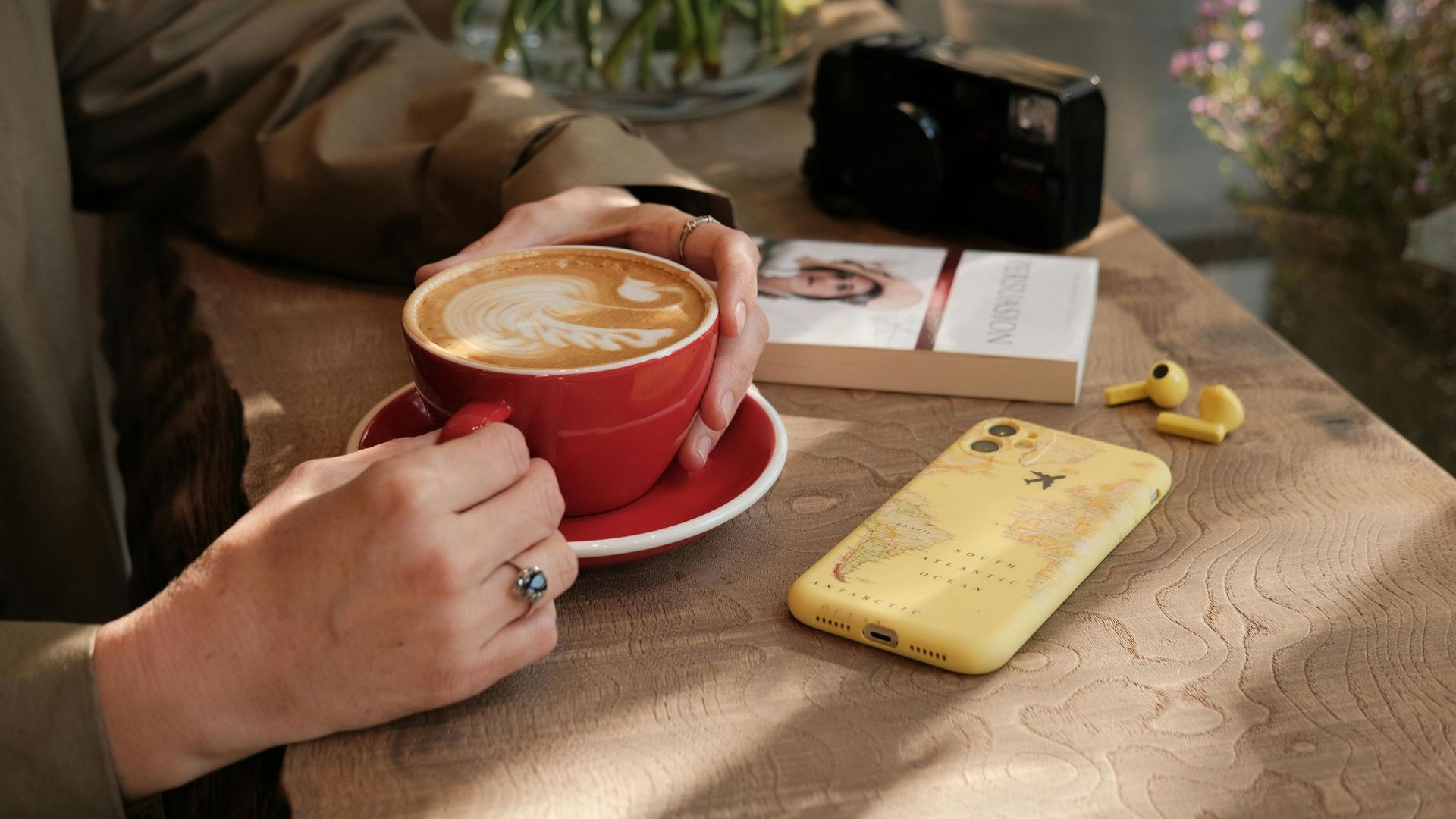 Una persona está sentada en una mesa sosteniendo una taza de café.