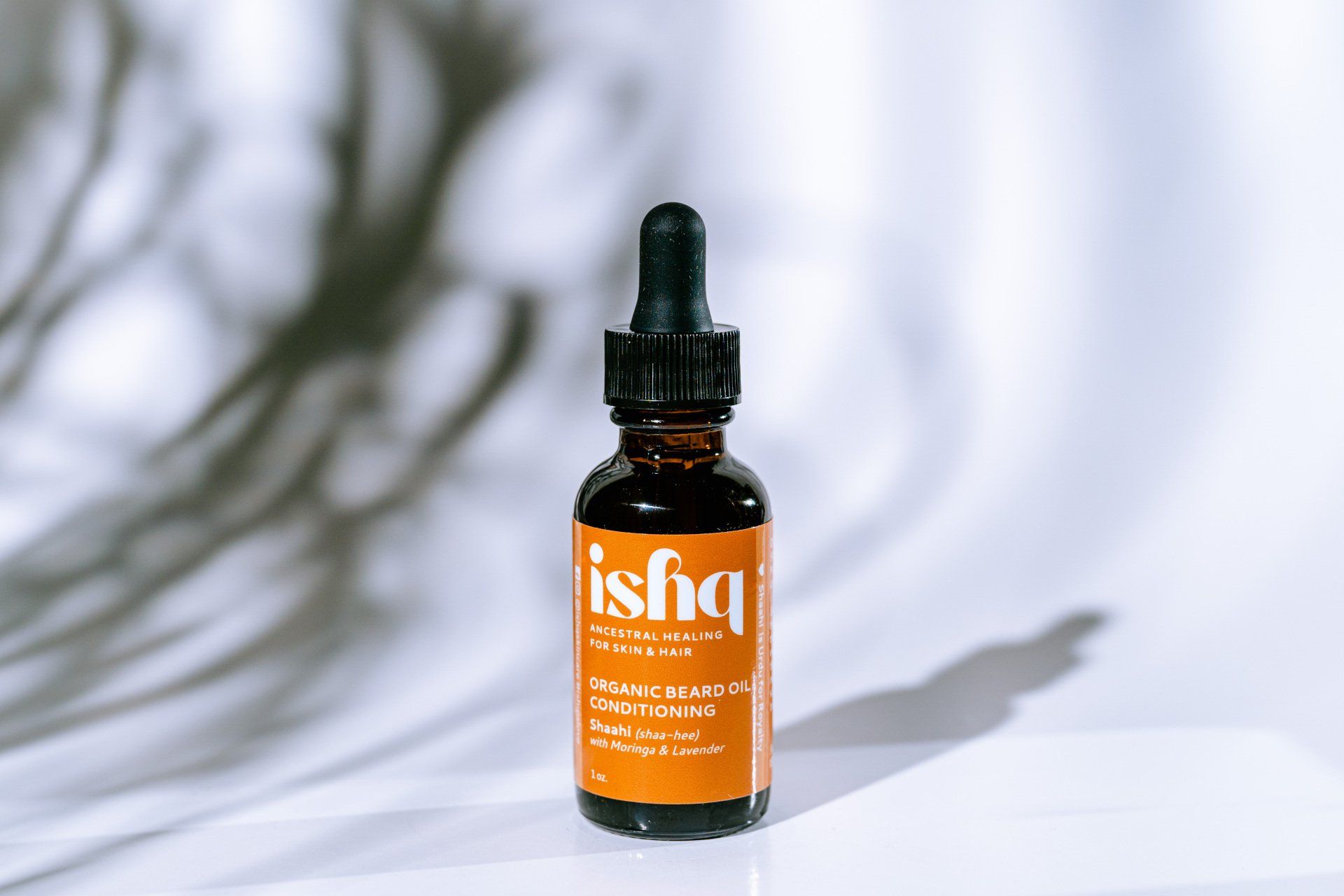 ishq Organic beard oil-conditioning blend. One ounce amber color bottle wrapped with a label that is a shade of brown.iIt has information about the beard oil, ingredients, directions of use