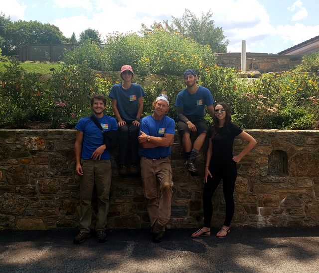 A group of people are posing for a picture in front of a stone wall