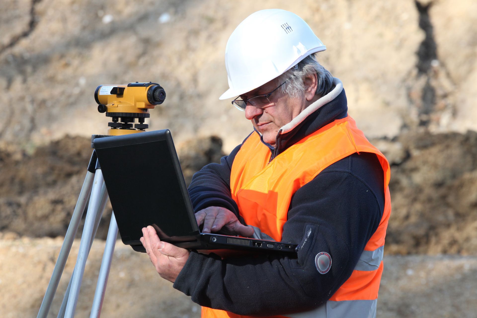 A surveyor outdoors working with a laptop and conducting a survey. A surveyor outdoors working with a laptop and conducting a survey.