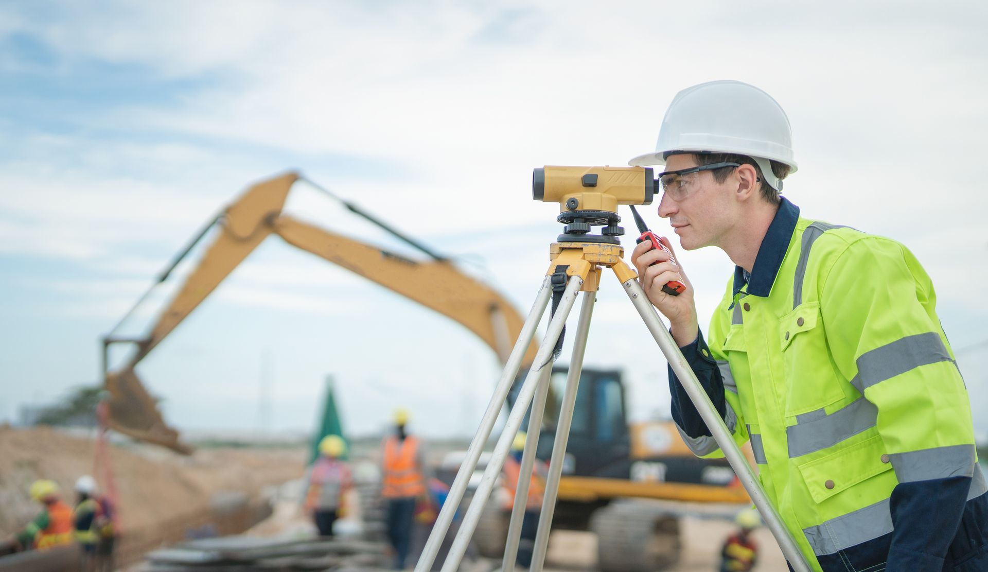 Male engineer working with survey equipment on construction site.