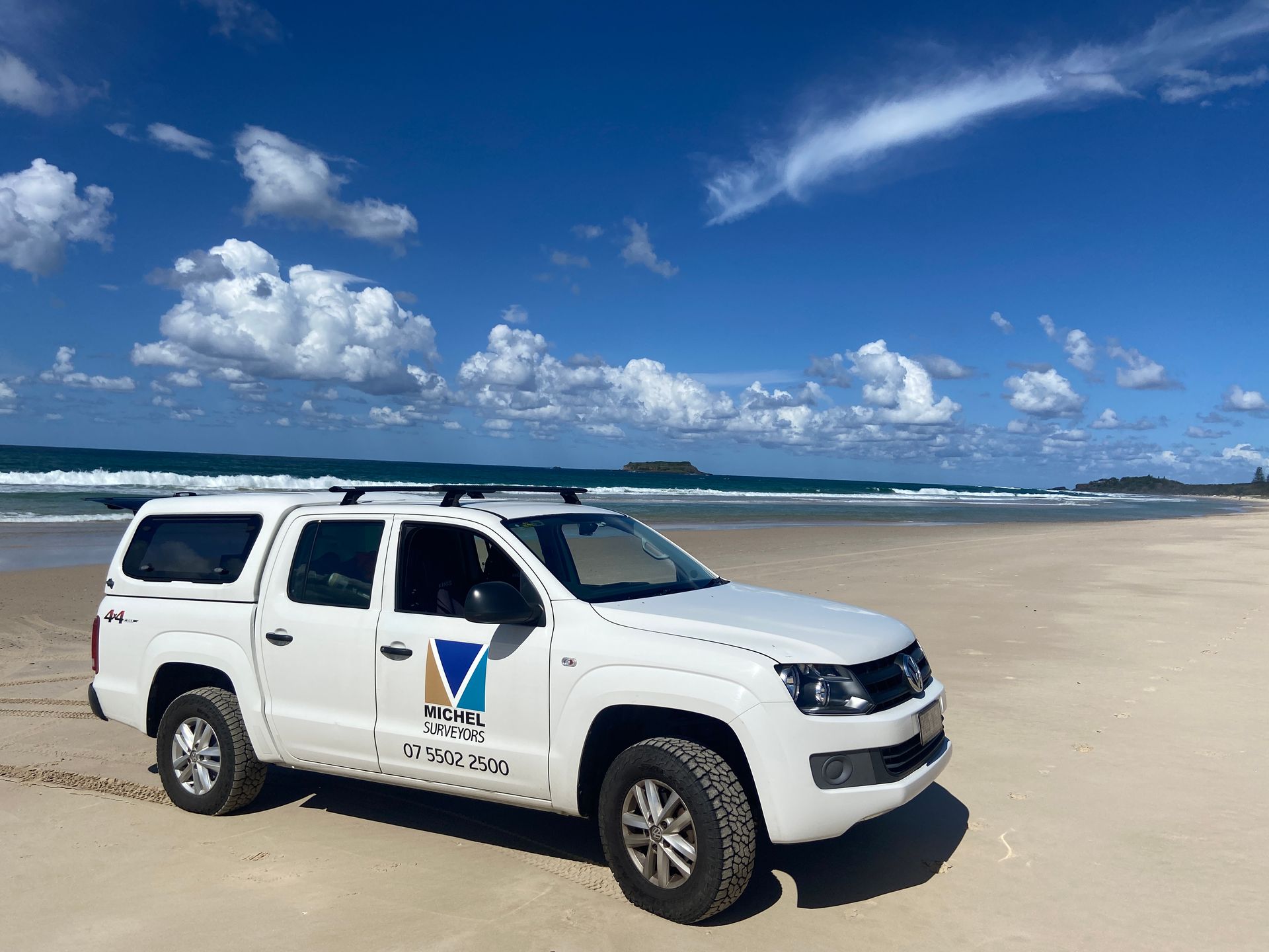 A white truck is parked on a sandy beach.