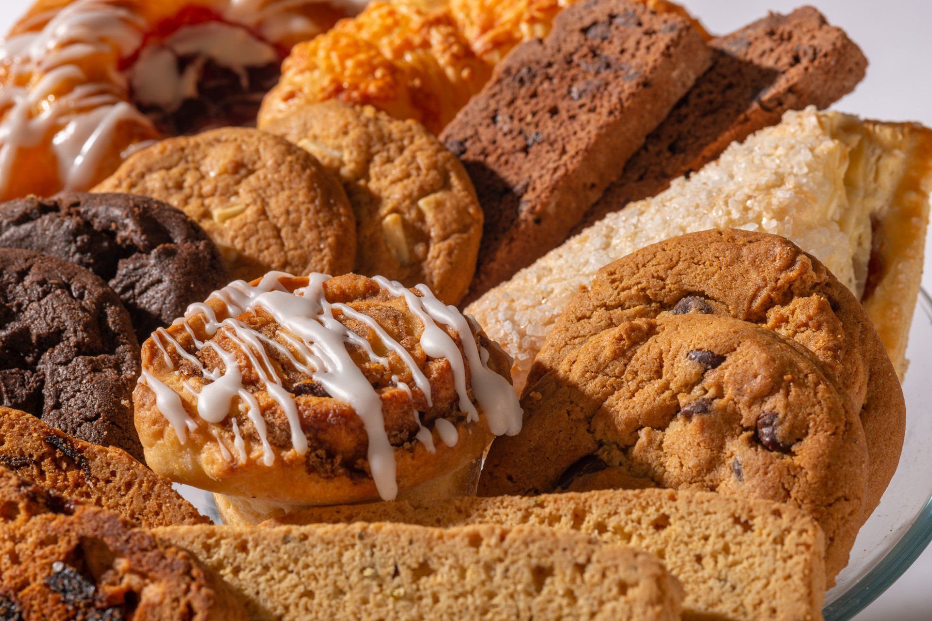 Assorted cookies and biscotti on a plate, some drizzled with white icing and caramel glaze