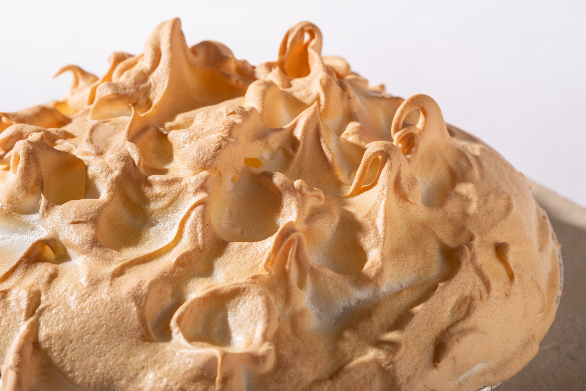 Close-up of fluffy golden-brown meringue peaks on a white background