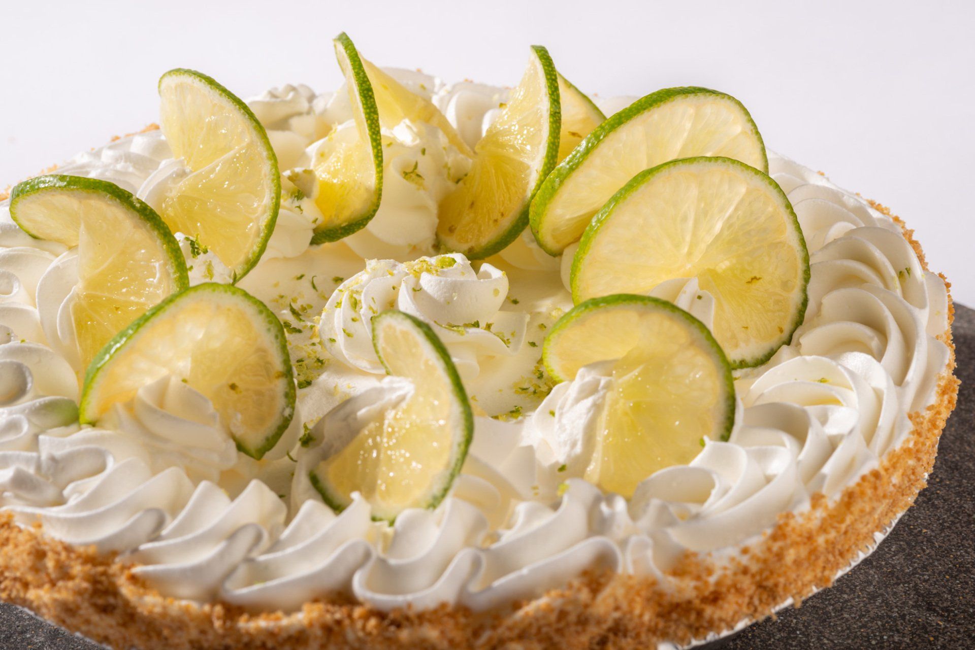Lime-topped cream tart with white frosting on a crumb crust