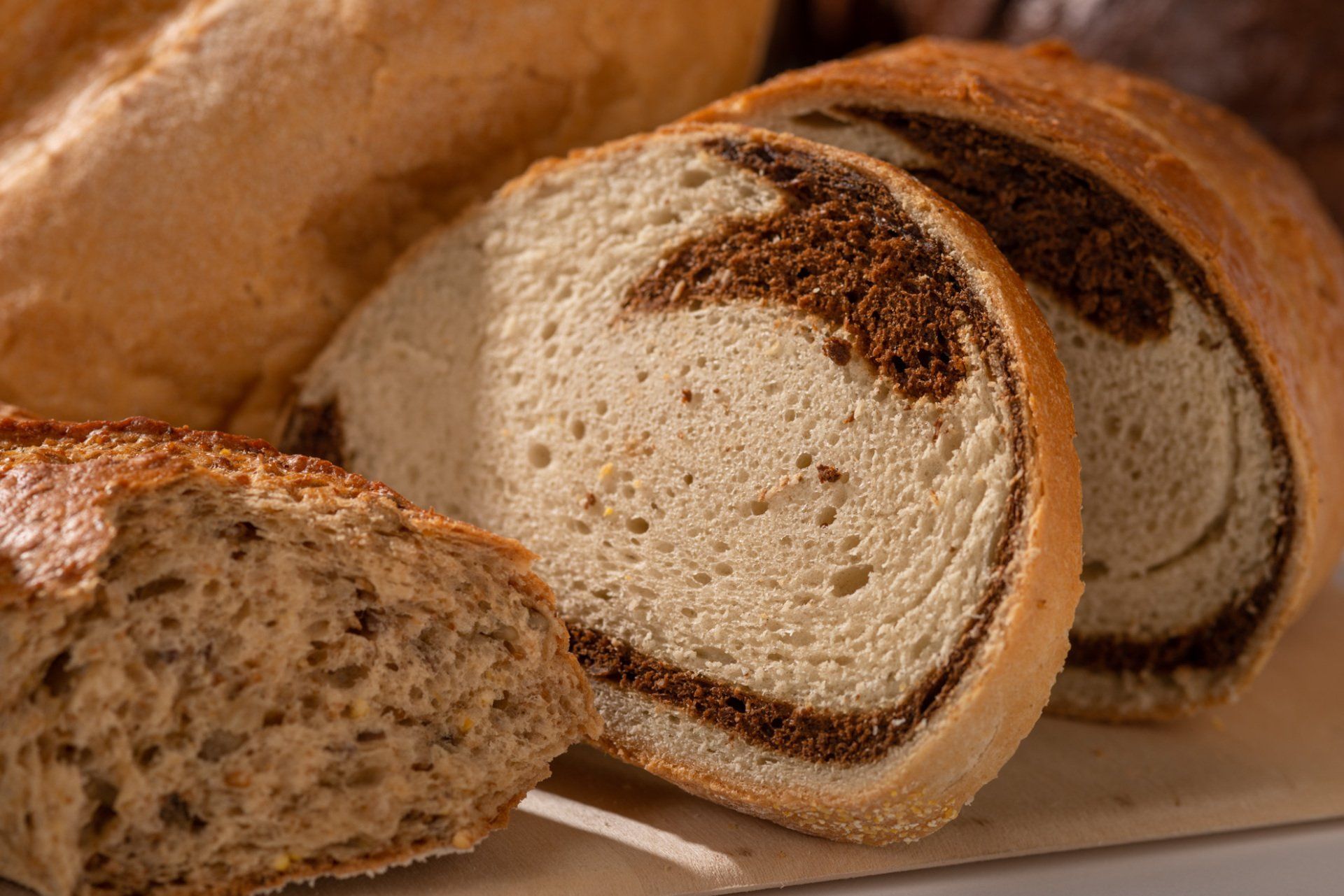 Sliced rustic loaf of bread with a brown crust and light crumb on a cutting board