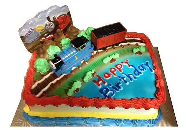 Colorful birthday cake with a train topper and “Happy Birthday” written in icing