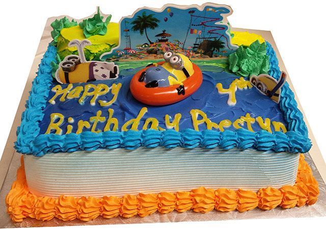 Blue birthday cake with “Happy Birthday Prathy,” beach scene toppers, and orange frosting trim