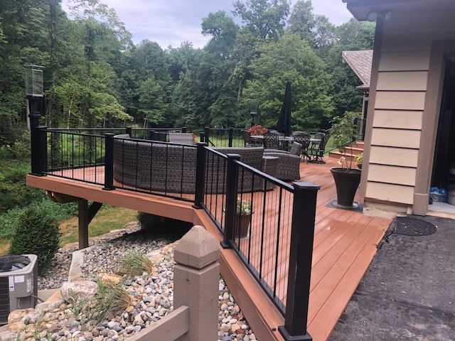 A wooden deck with a black railing and a couch on it