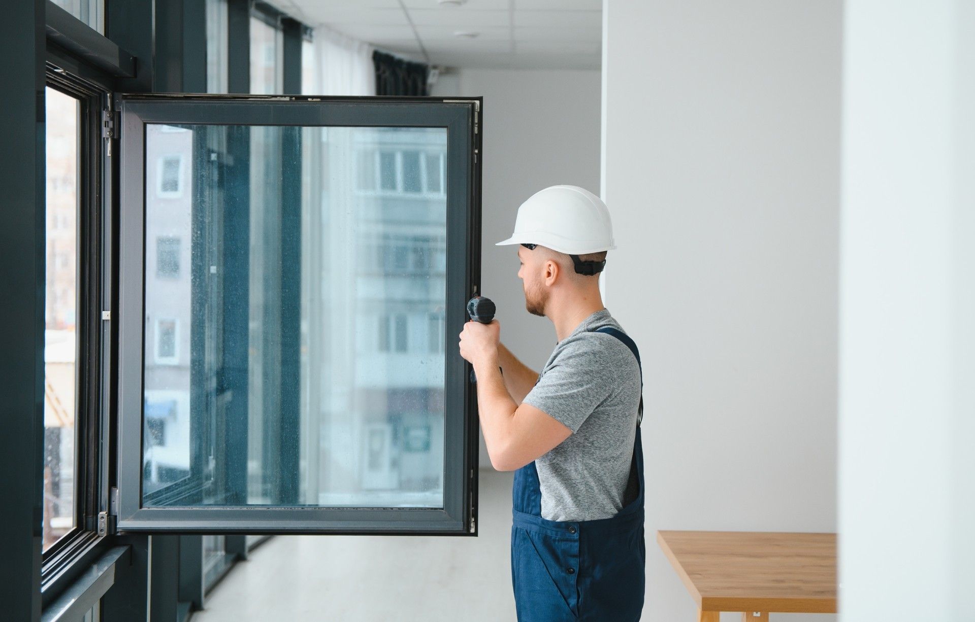 A man is installing a window with a drill in a room.