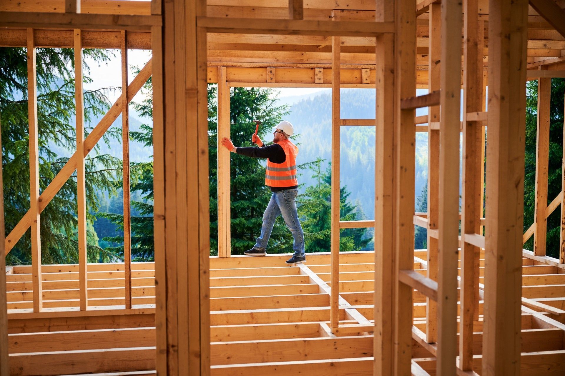 A man is standing in a wooden frame of a house under construction.