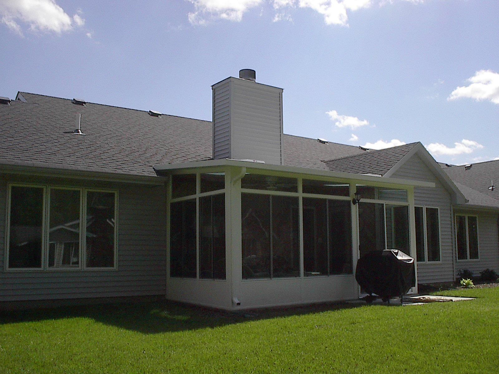A house with a screened in porch and a chimney