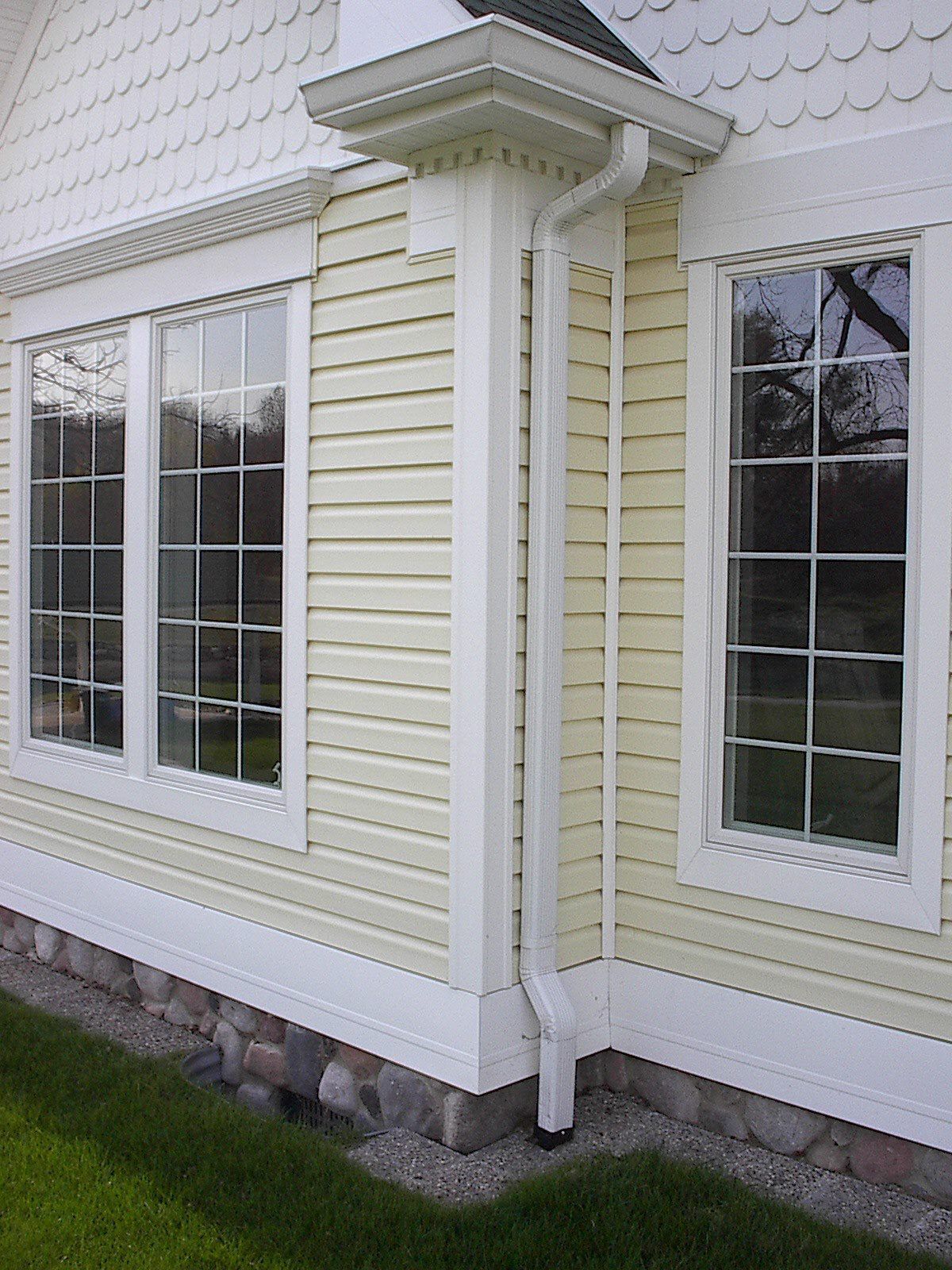 The side of a house with yellow siding and white trim