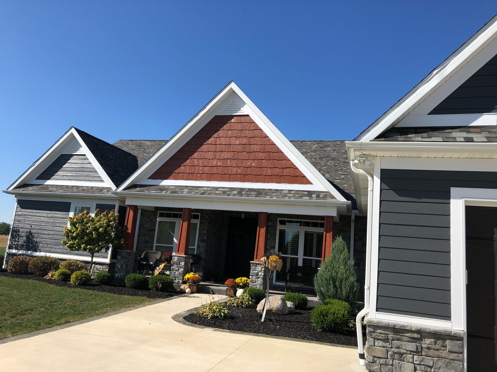 A large house with a gray siding and a red roof